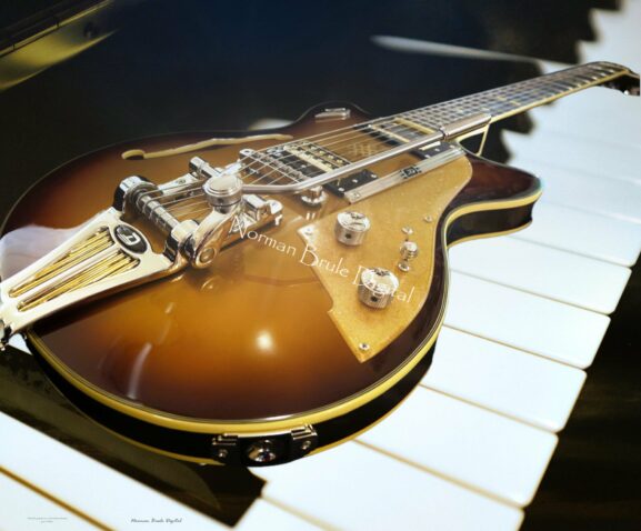 A guitar lies on a piano background.